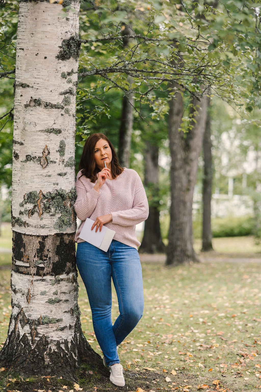 Murumedian yrittäjä Mari-Anna Rossi nojaa koivuun puistossa.